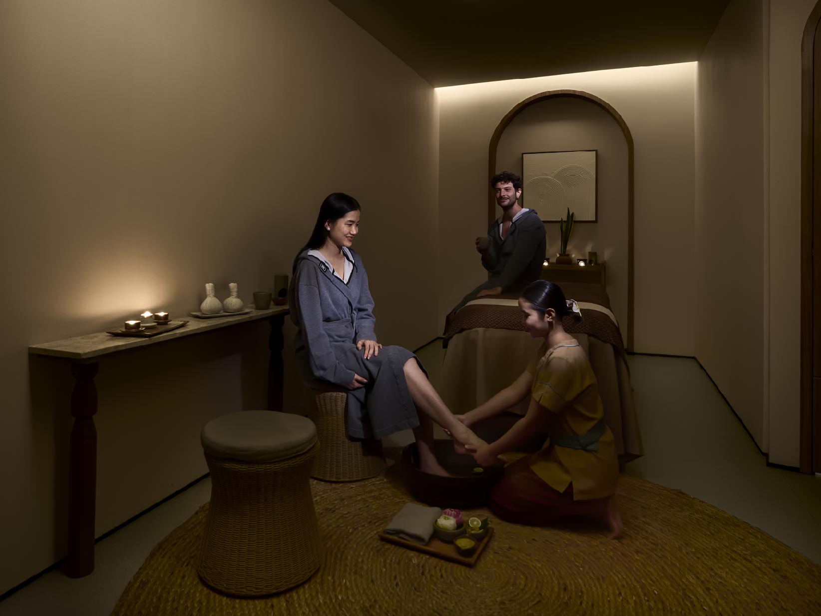 Two people receive foot treatments in a softly lit spa room.