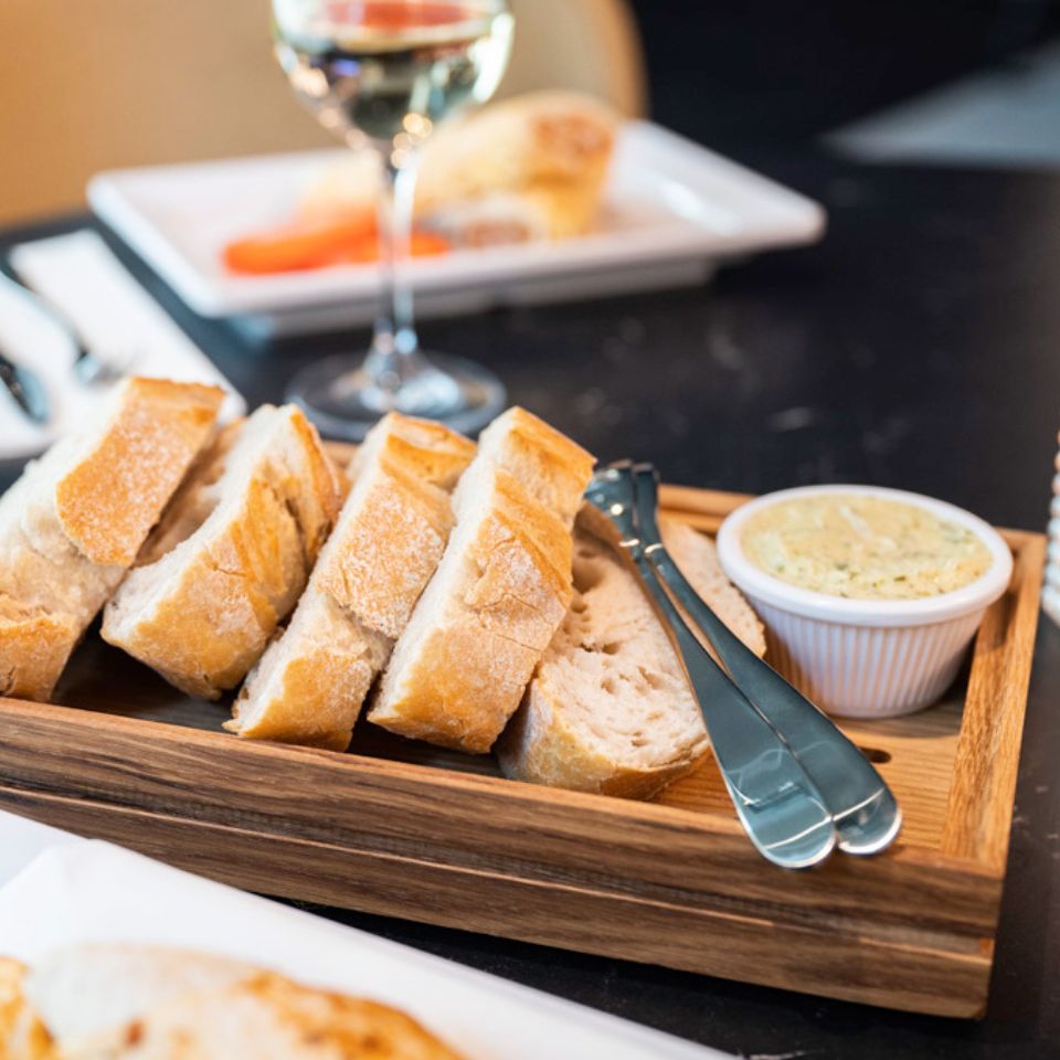 Sliced bread and a small dish on a wooden serving board.