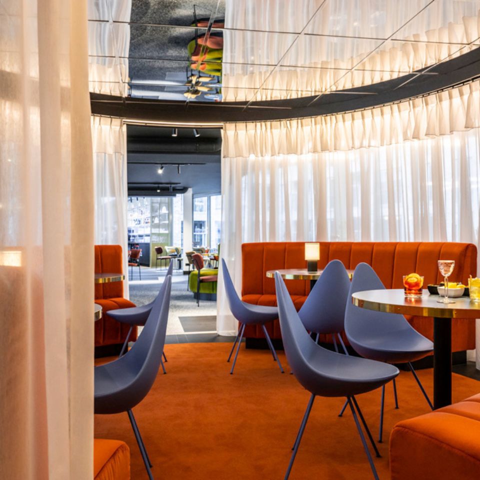 Restaurant tables with blue chairs and orange banquette seating.