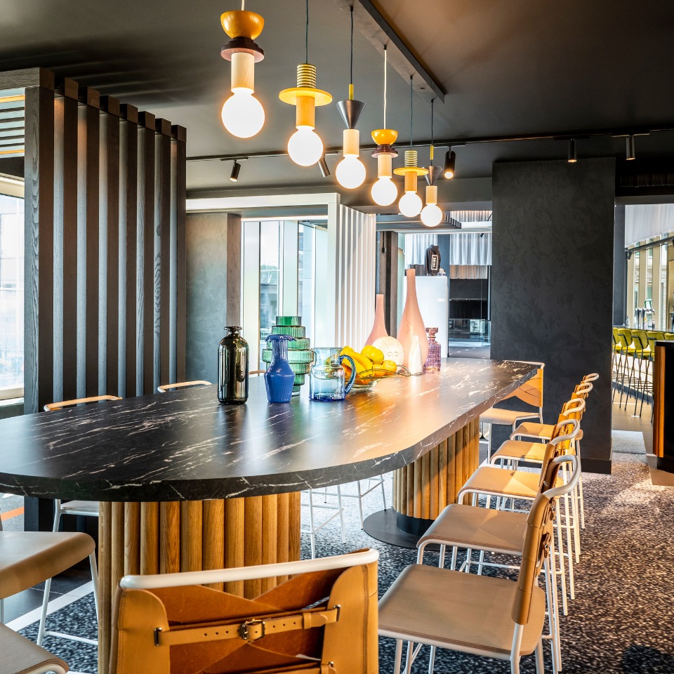 Long curved bar counter with stools and pendant lights.