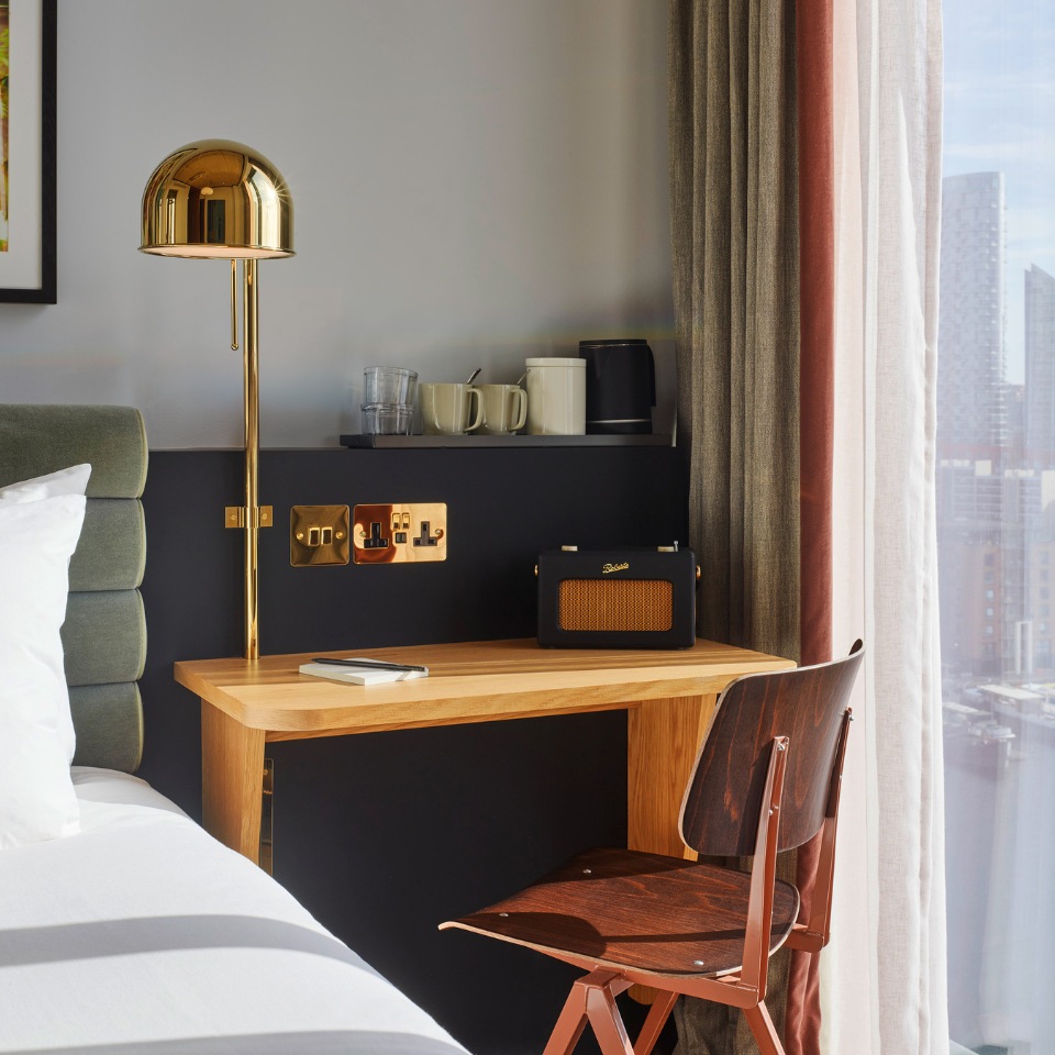 Bedroom desk and coffee station beside a bed.