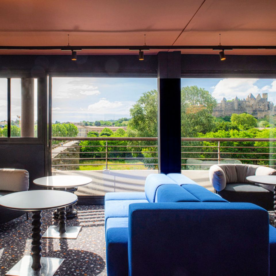 Hub with multiple armchairs and couches, with access to a balcony with spectacular view of medieval city
