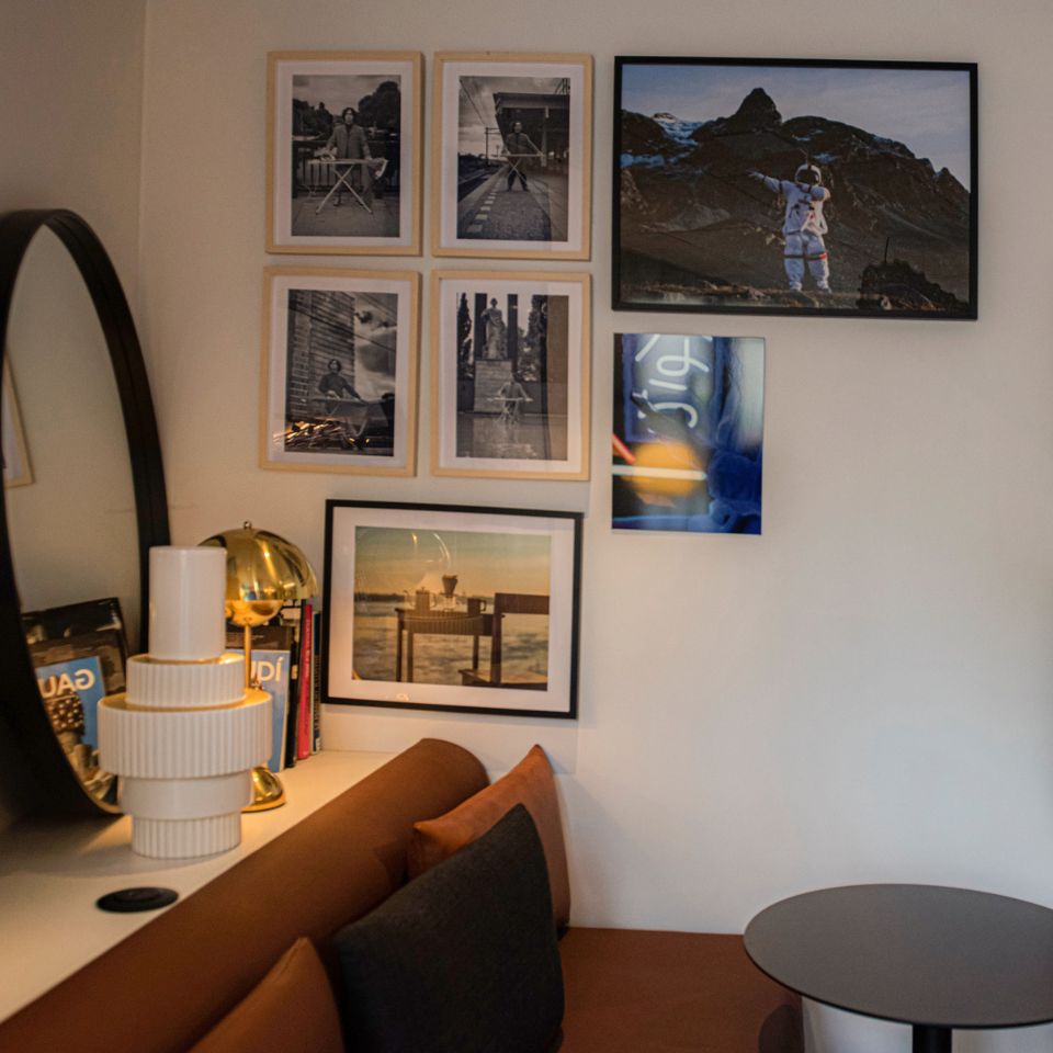 Lounge corner with framed pictures, mirror, sofa and small tables.