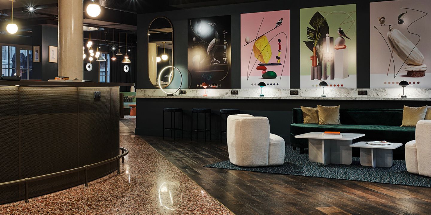Common area at TRIBE Le Touquet with colourful artwork on the wall and couches and armchairs around coffeetables