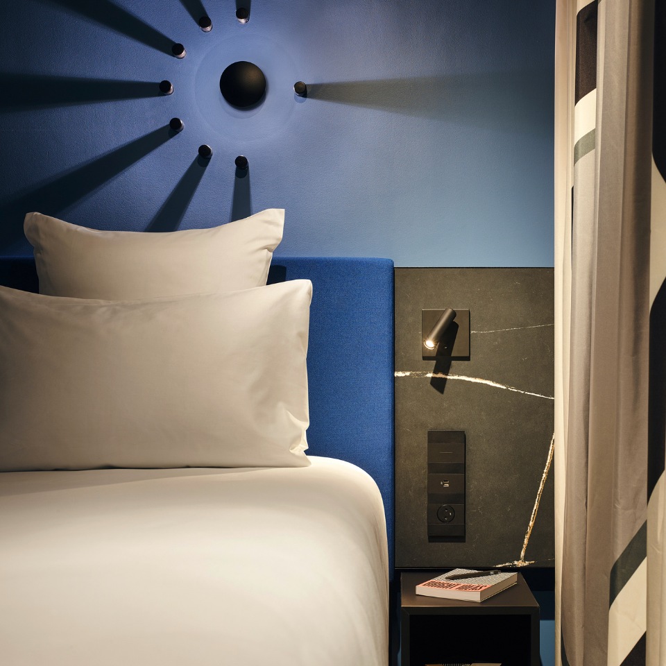 White bed against a blue wall with a sunburst decoration.