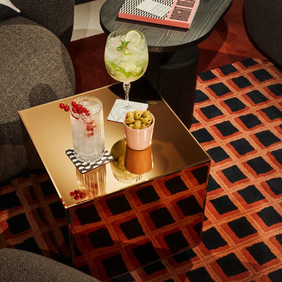 A small, golden table with olives and two drinks on coasters