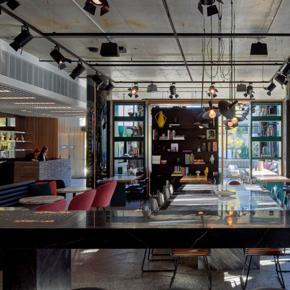 several tables and chairs, in the background is a shelf with books and decoration and the reception