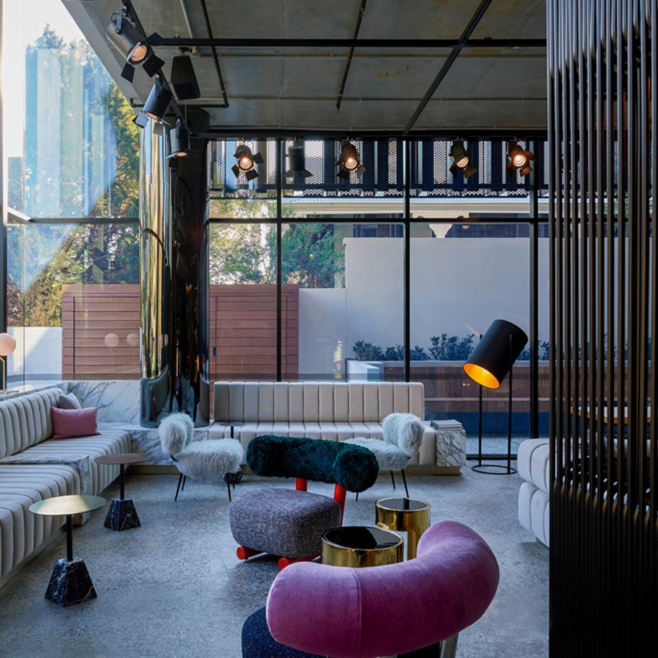 Two couches and several cozy chairs in bright colours in a room with floor to ceiling windows