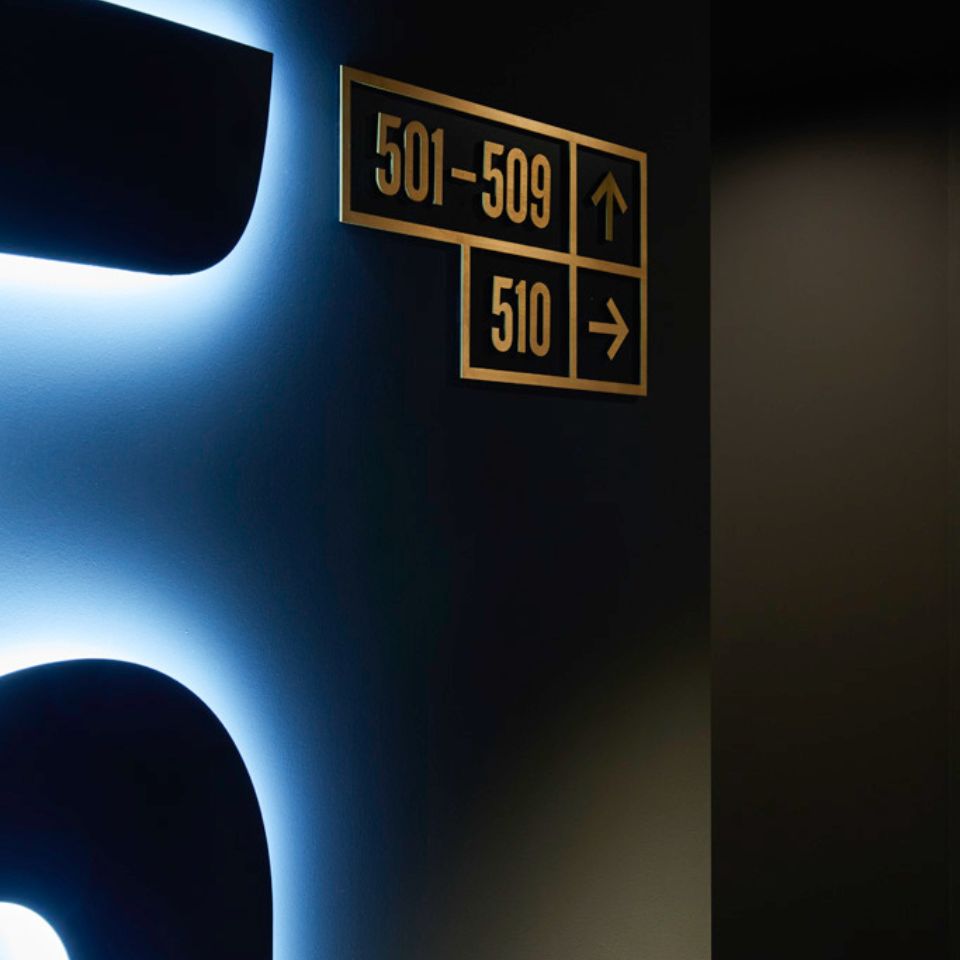 Illuminated floor number 5 beside room direction signs.