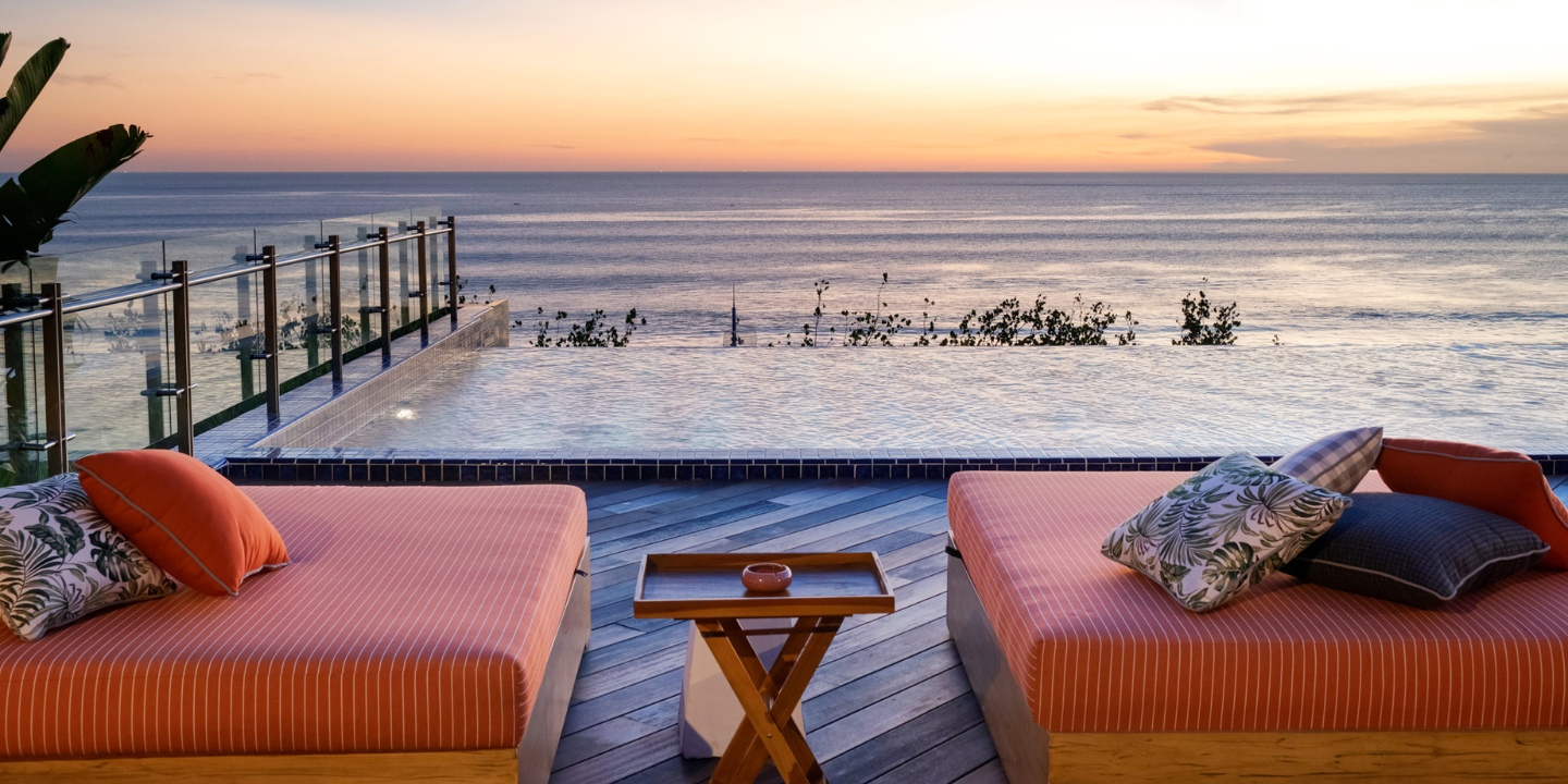 View of the ocean and the rooftop pool with orange lounge furniture
