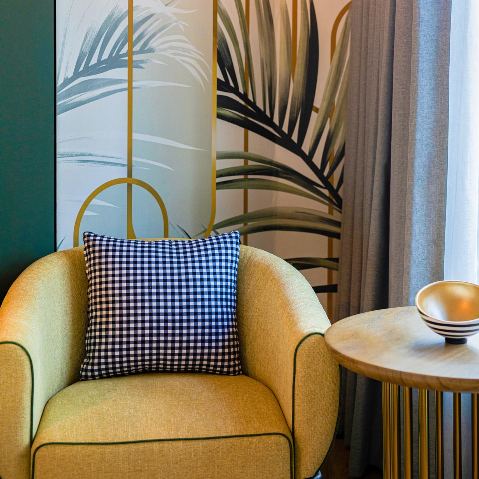 A yellow armchair with a pillow next to a small nightstand