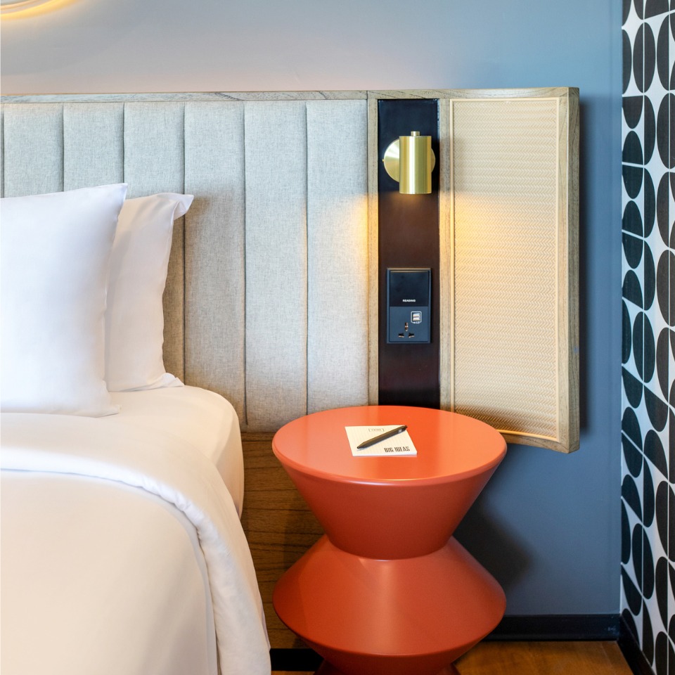 A double bed with an orange nightstand