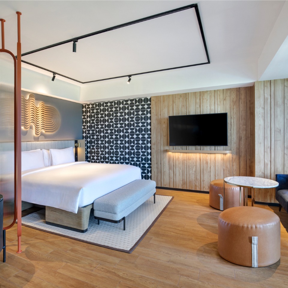 Suite at TRIBE Bali Kuta Beach with a double bed, and a TV, one of the walls is designed with eye-catching black and white symbols