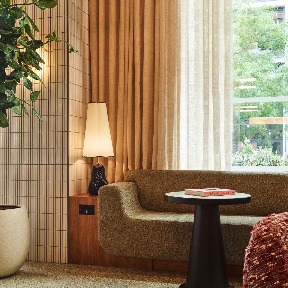 A small couch in front of a window and a black table