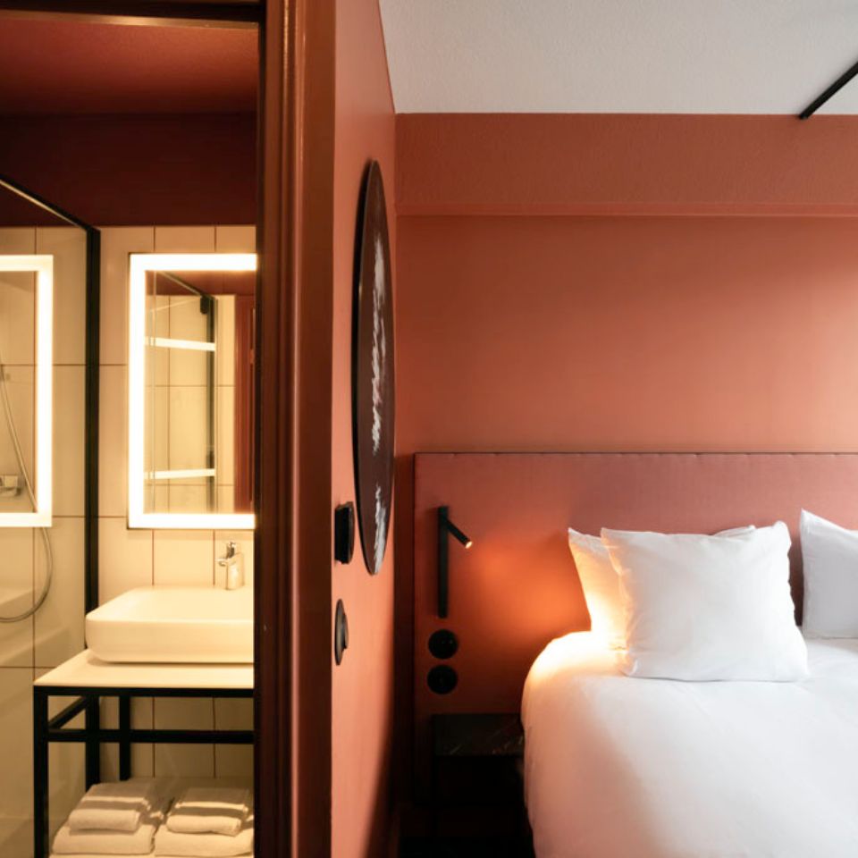 Split view of double bed and stylish bathroom with illuminated mirror