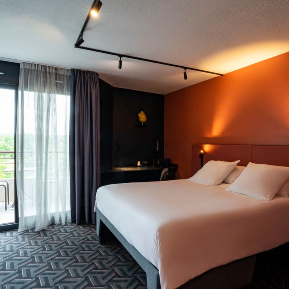 Hotel room with double bed and sliding glass door leading to a balcony