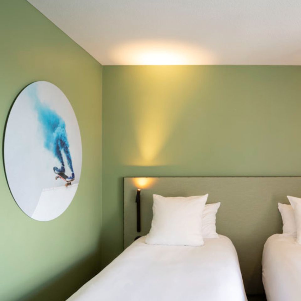 Hotel room with two single beds and a wall mounted artwork depicting a skateboard