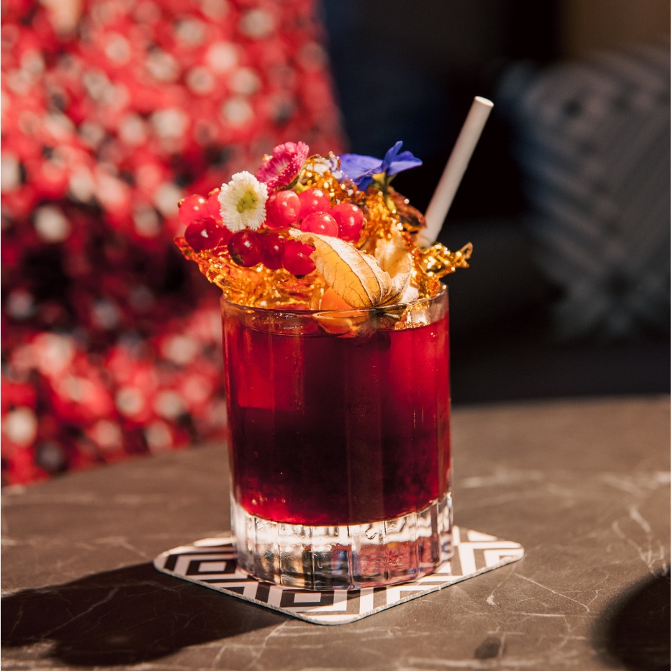 A colourful drink with fruits and flowers on top
