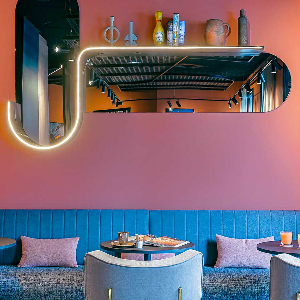 Comfortable blue couches and armchairs and mounted mirror reflecting the room