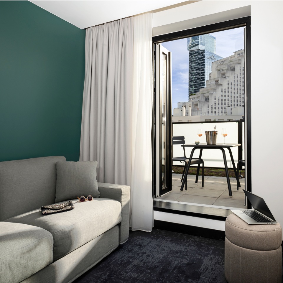 Hotel room with a grey couch and a view on to the balcony