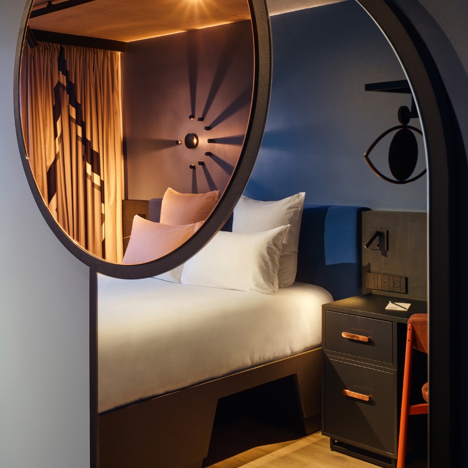 Bedroom reflected in a large round mirror.