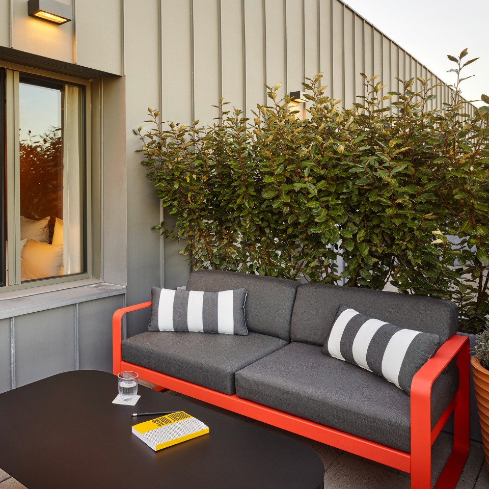 A terrace with a grey and red sofa in front of a black table