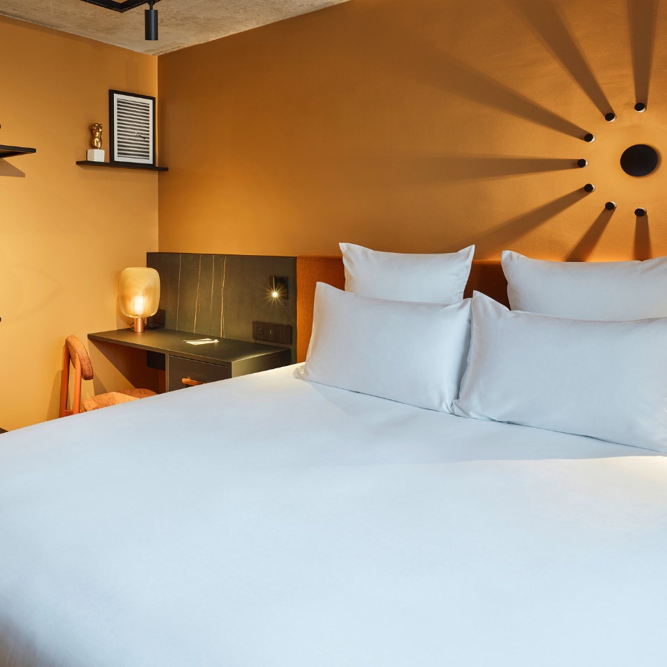 White pillows beneath a sunburst decoration on a yellow wall.