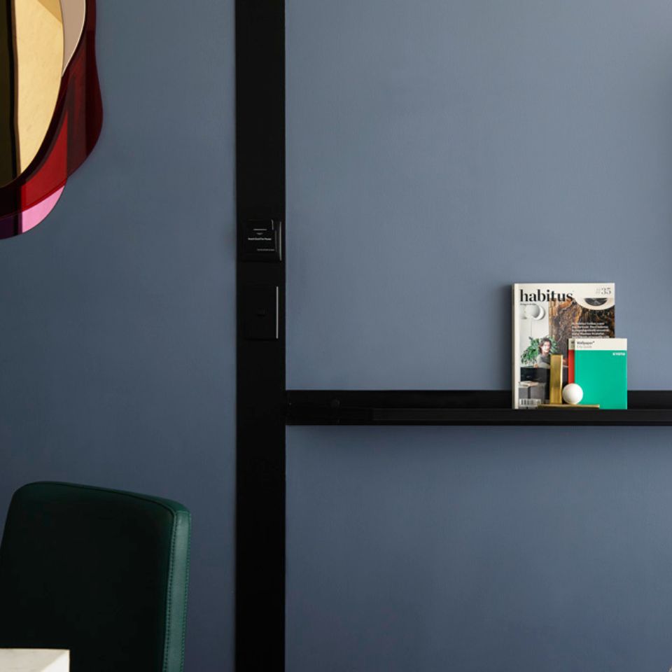 Dark shelf beneath a mirror on a blue bedroom wall.