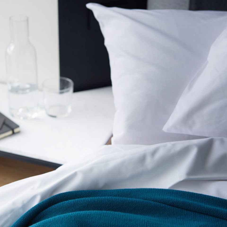 White pillows and bedding with a turquoise throw.