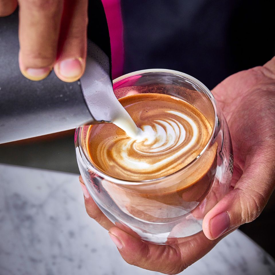 Latte art réalisé par un barista dans une tasse transparente