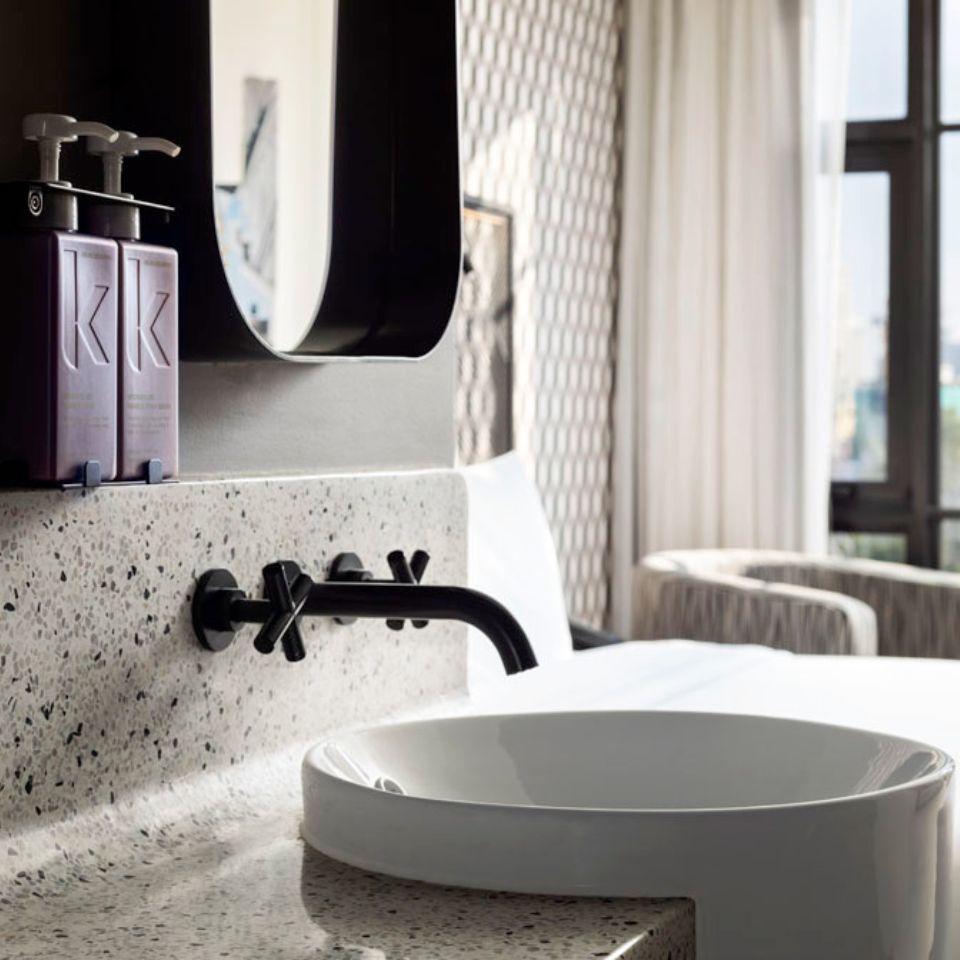 White basin, black tap and mirror beside a bathroom window.