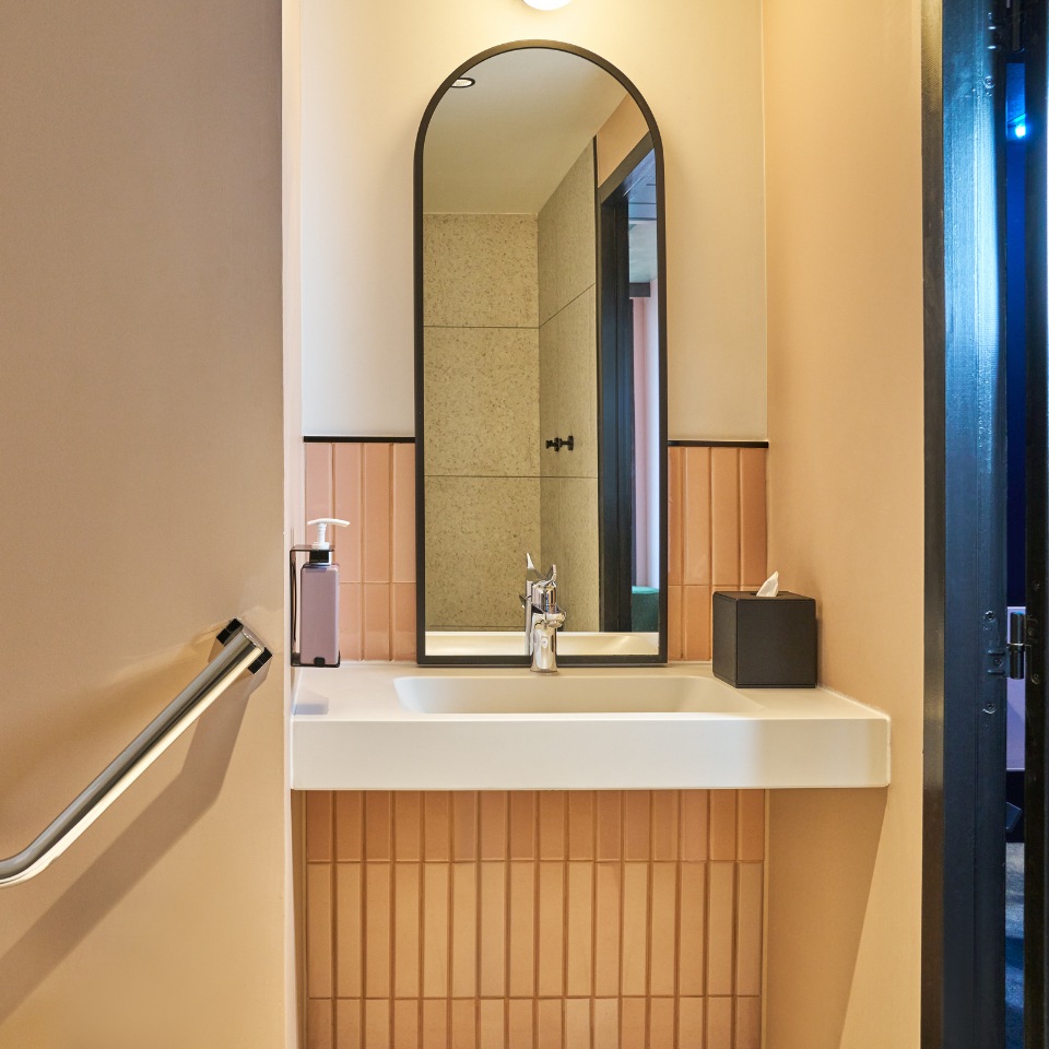 Sink and tall arched mirror above a wooden vanity.