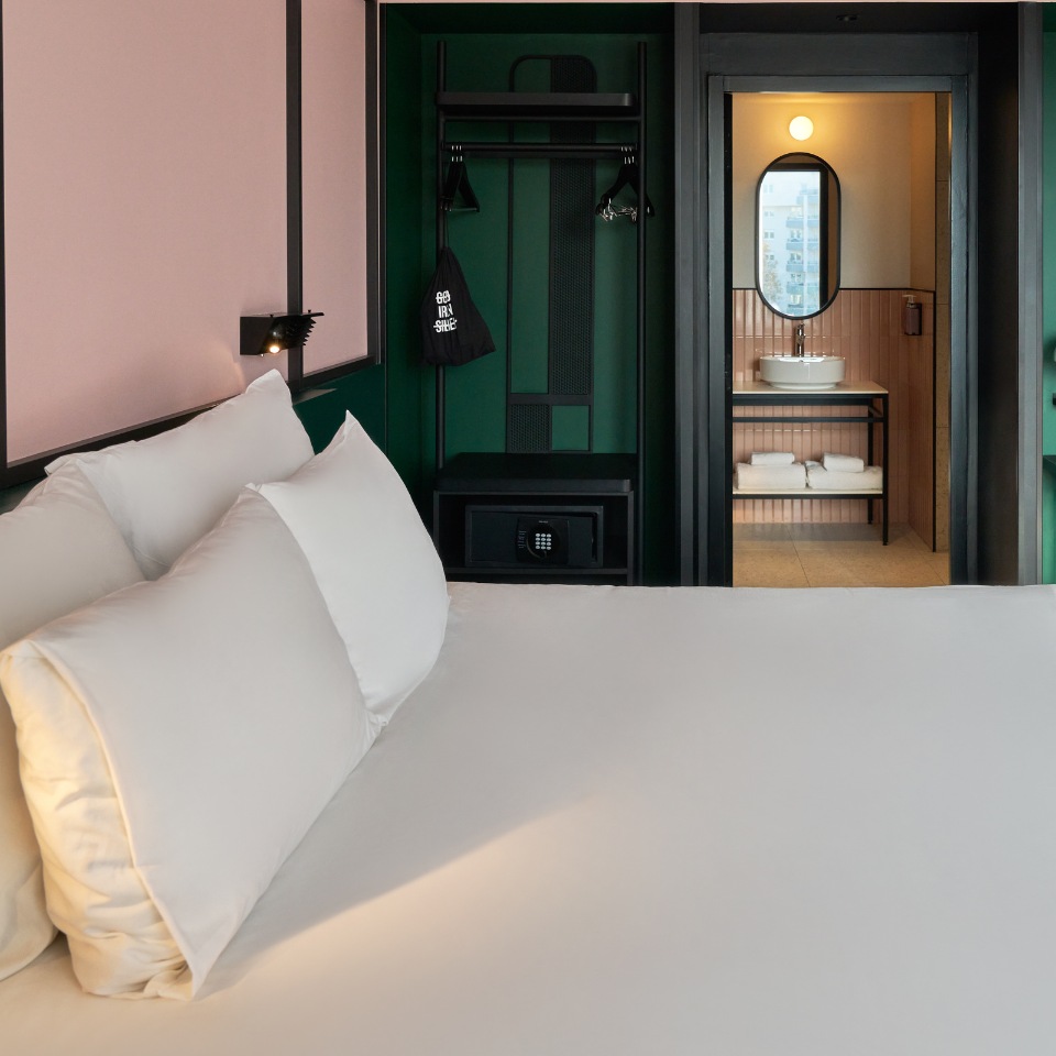 White bed beside a green alcove leading to a bathroom.
