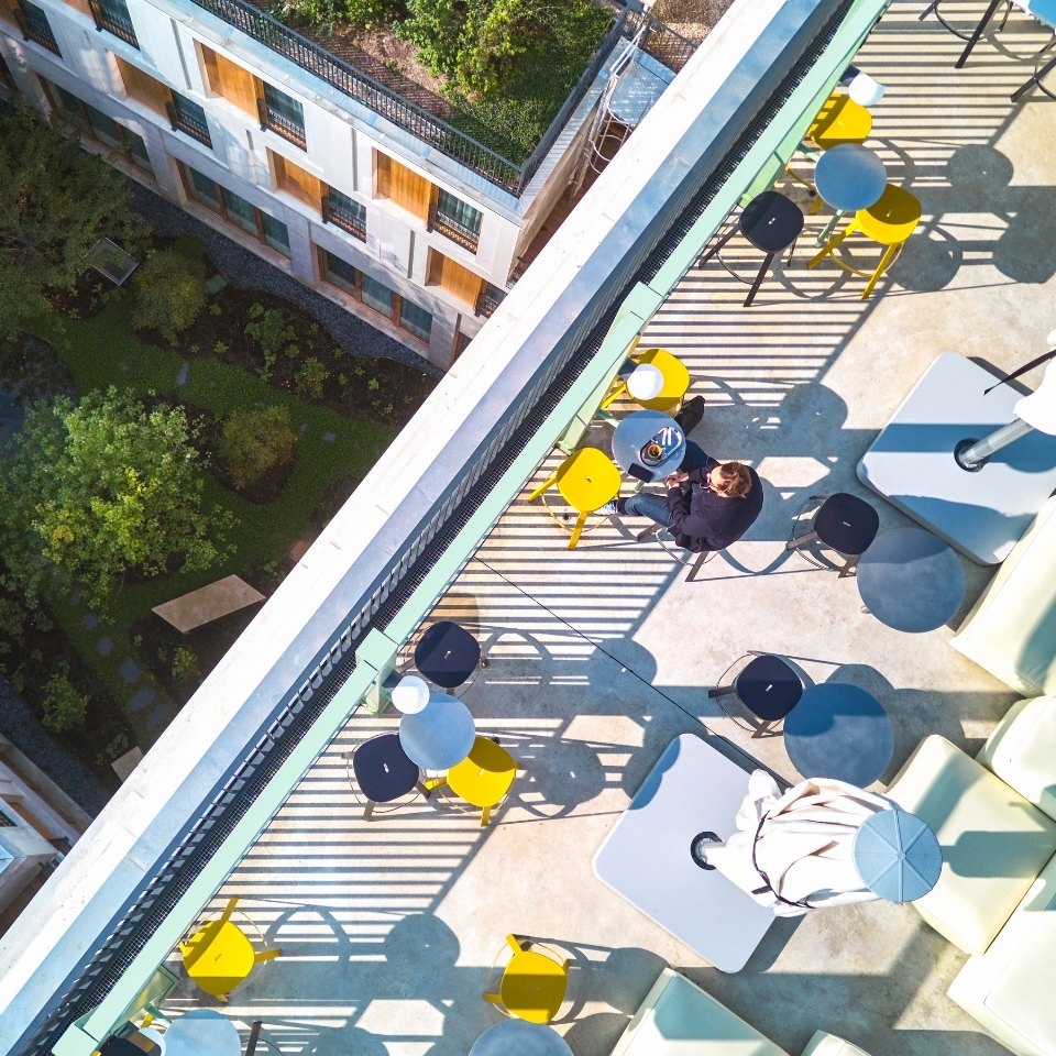 Overhead view of a rooftop terrace with colourful tables and chairs.