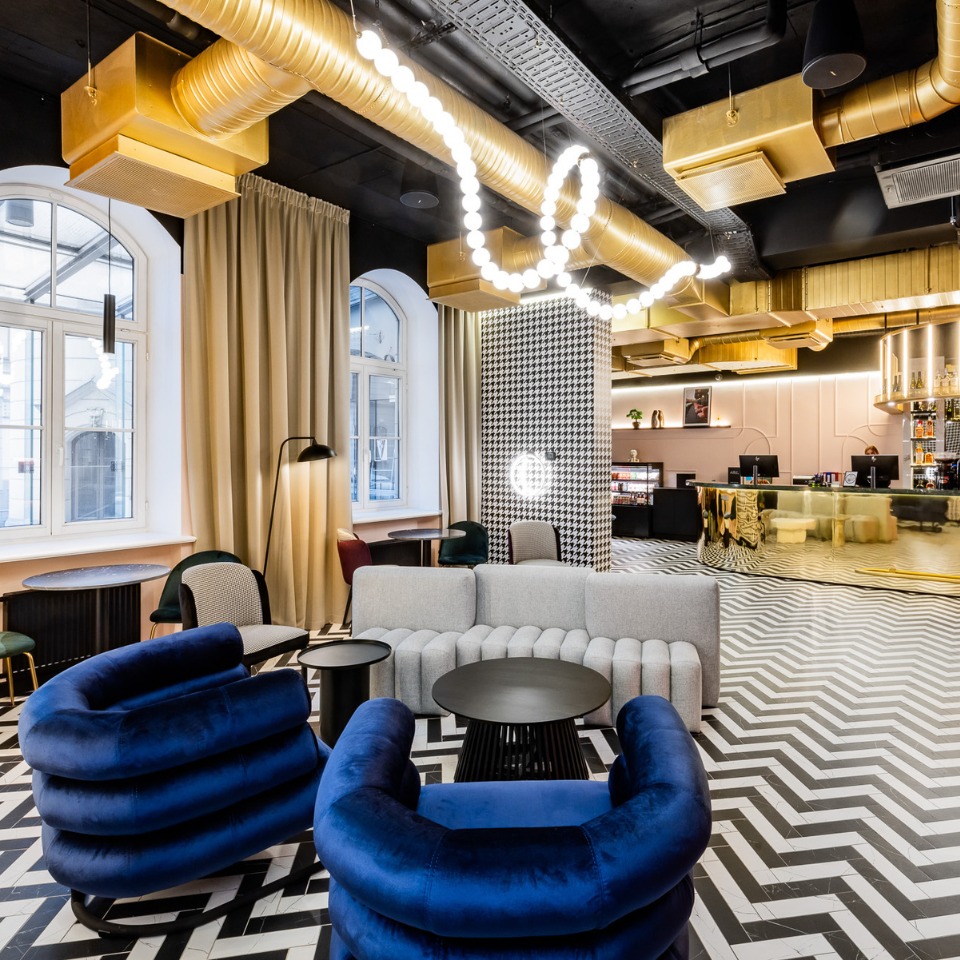 Lounge with blue armchairs, striped flooring and exposed metallic ducts.