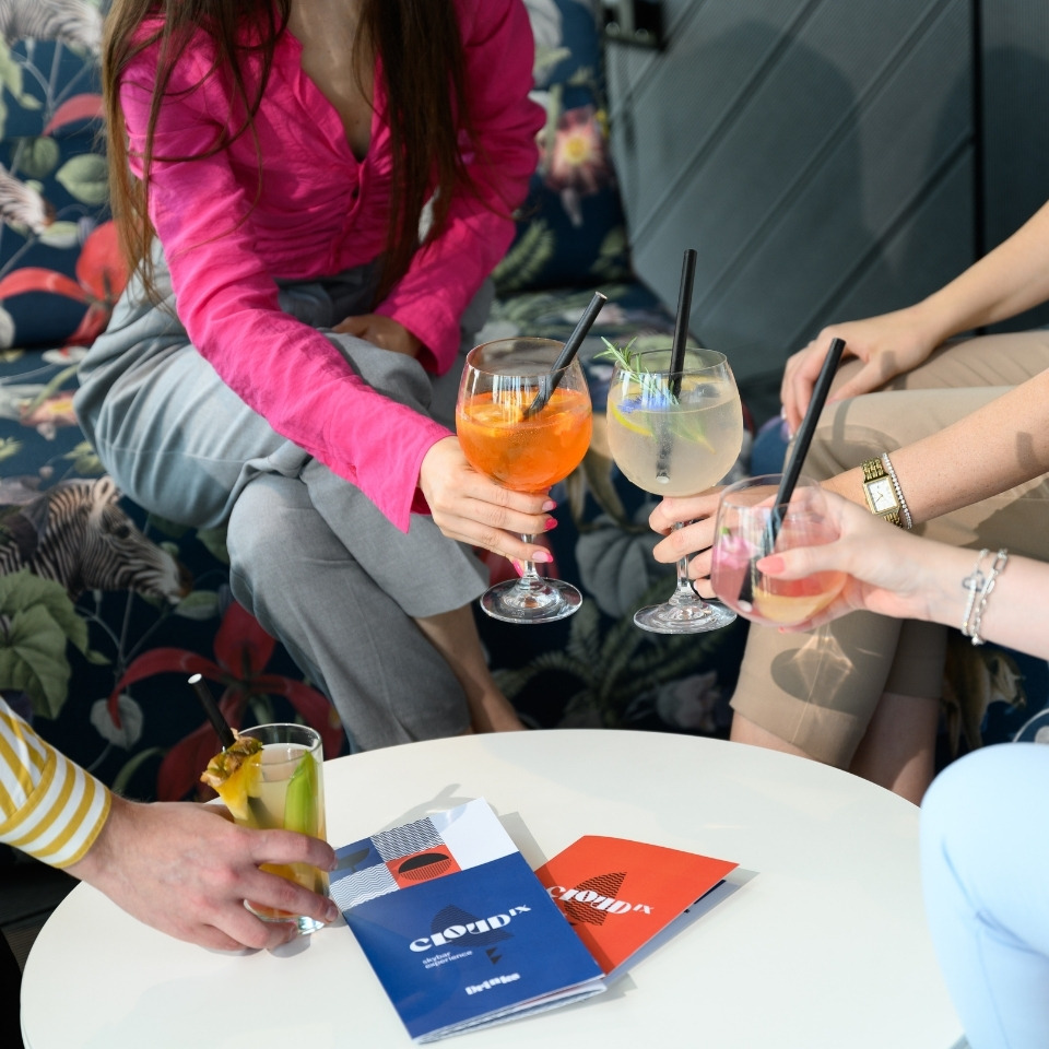 Friends raise colourful drinks around a small round table.