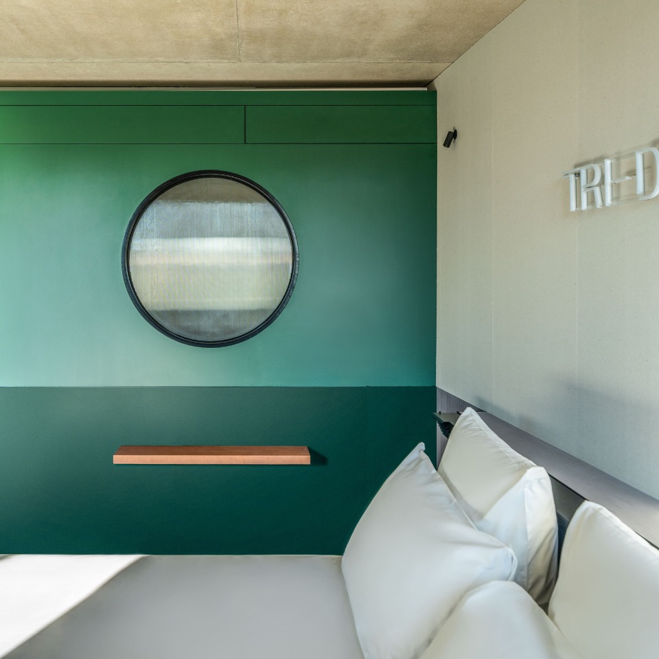 Lit près d’un mur vert avec miroir rond.