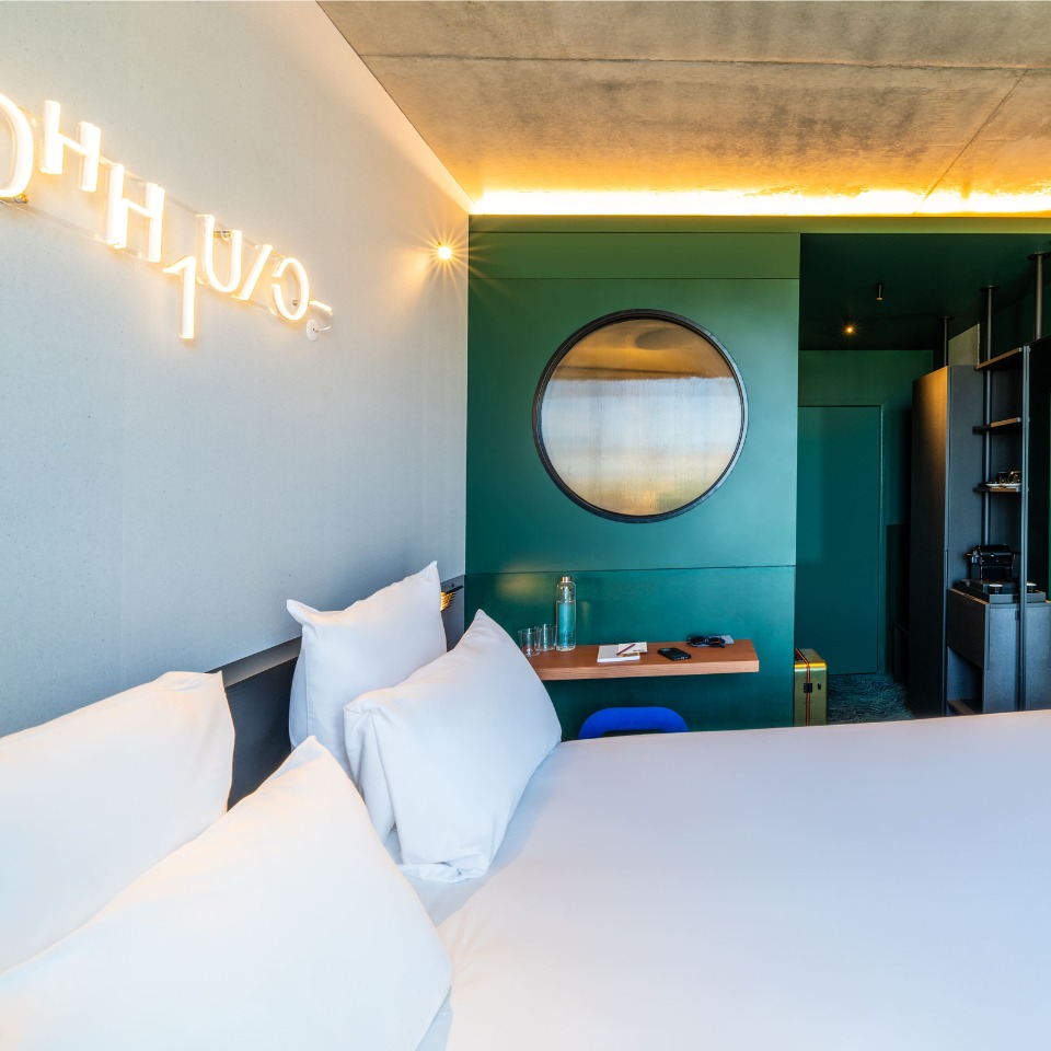 Lit près d’un mur vert avec miroir rond.