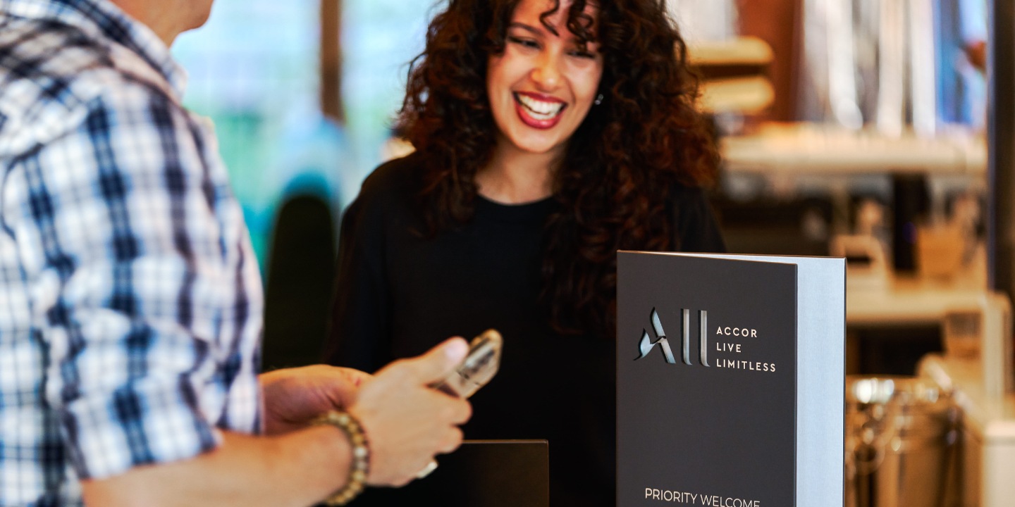 A guest being welcomed at reception beside an ALL Accor Live Limitless sign.