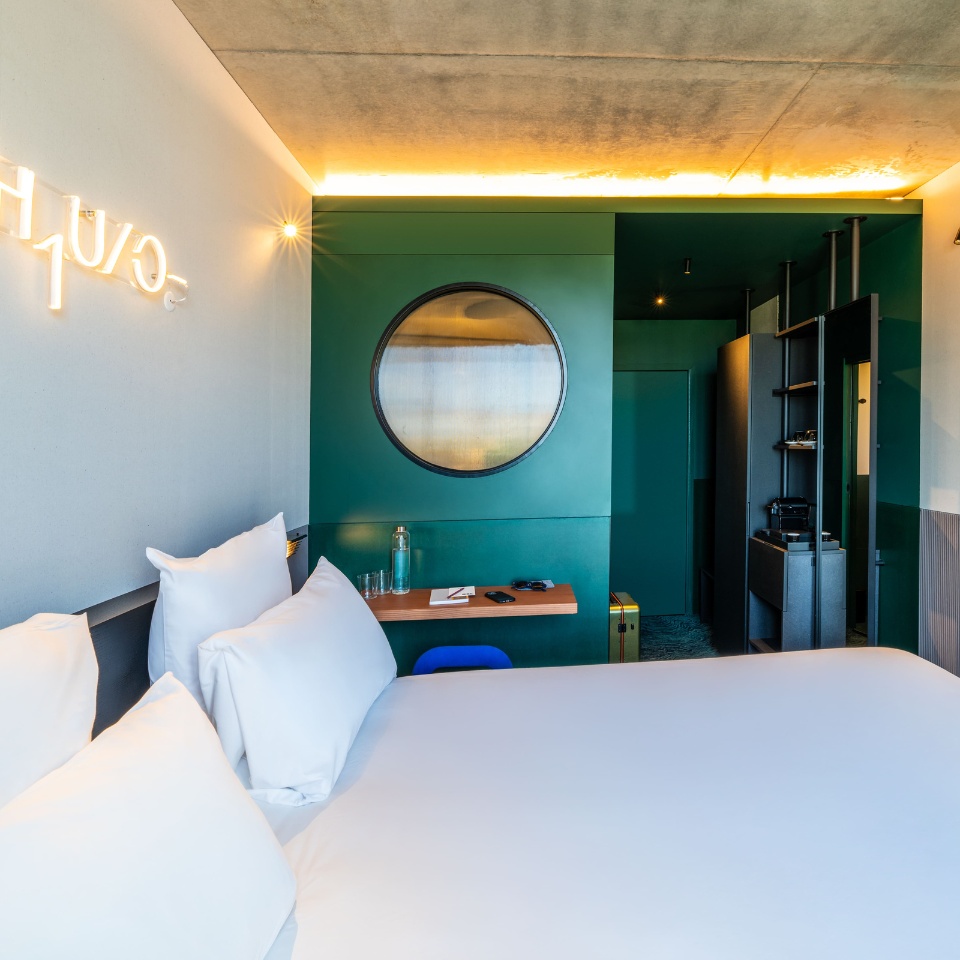Guest room with a double bed and a green wall with a round opening.