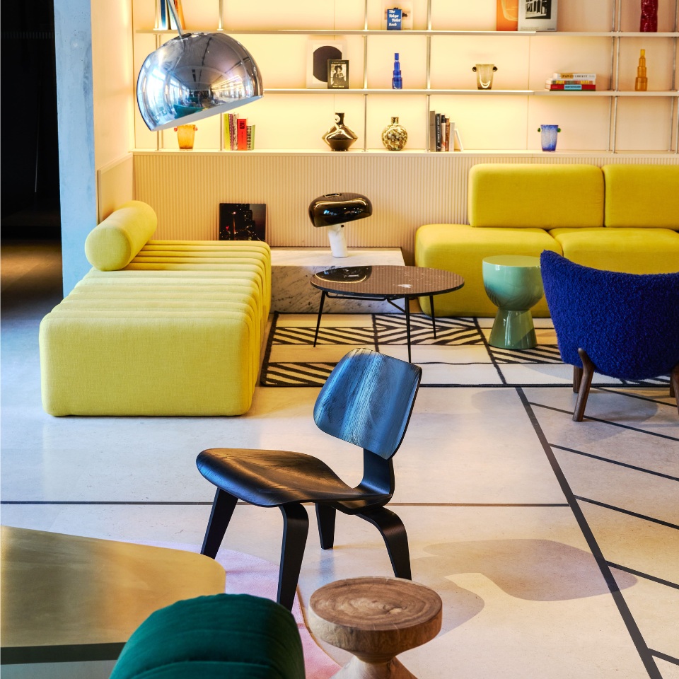 Lounge with yellow sofas, a blue chair and a large chrome lamp.