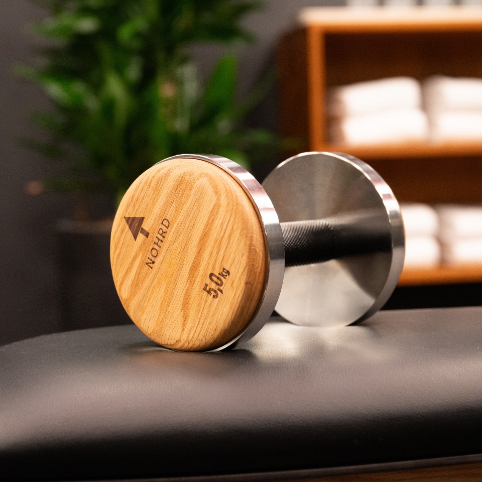 A 5 kg wooden and metal dumbbell on a black bench.
