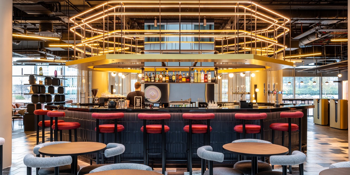 A modern bar with stylish seating, atmospheric lighting, and a bartender preparing drinks, in a contemporary lounge setting.
