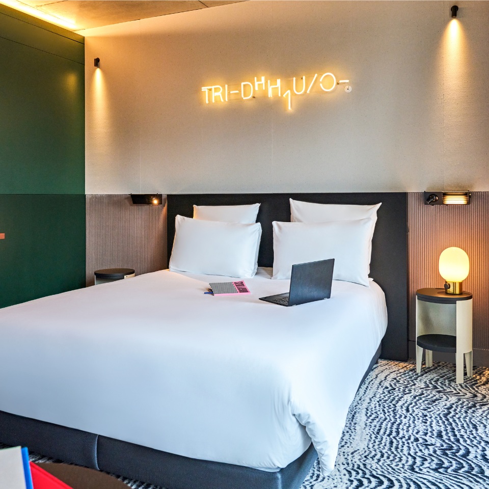 Chambre avec un grand lit blanc, un ordinateur portable et des luminaires.