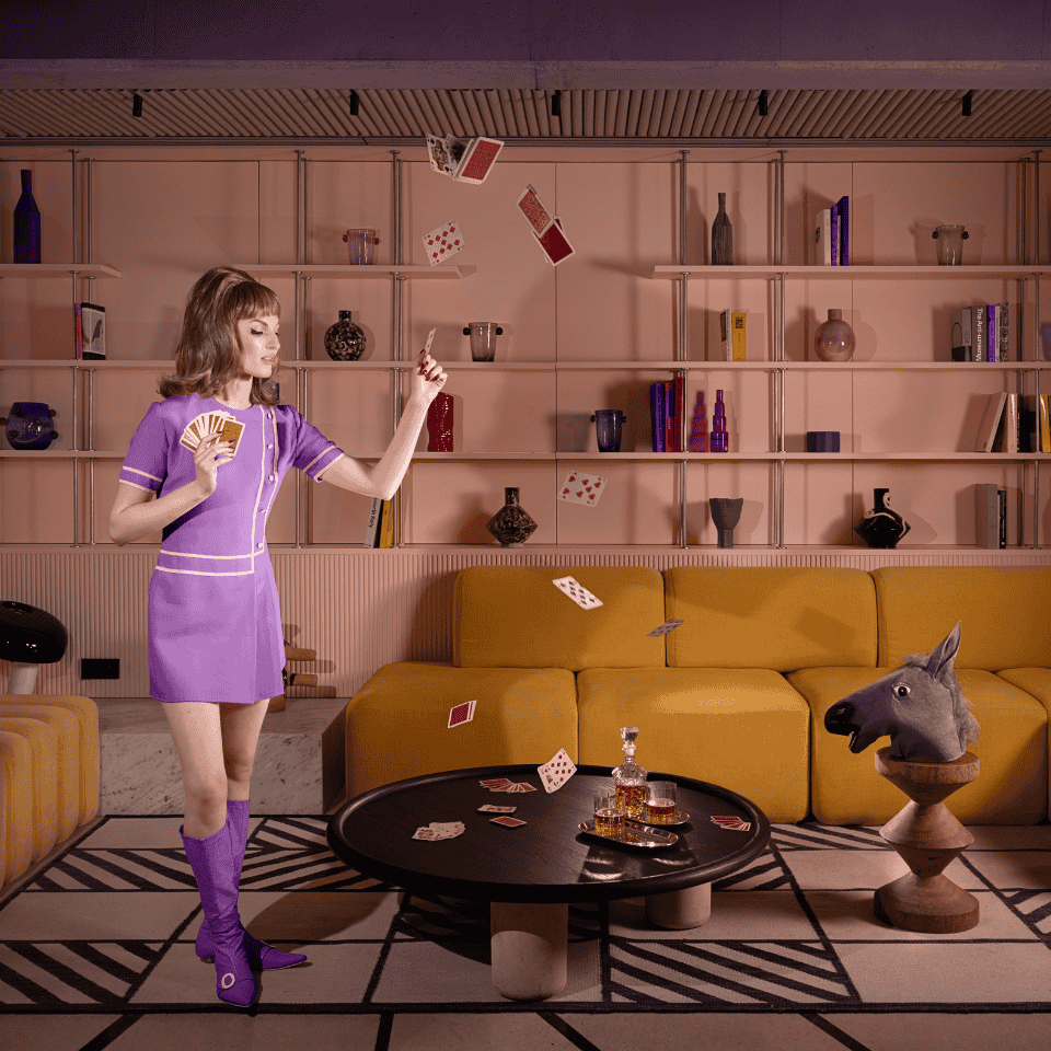 A performer in purple juggles beside lounge seating.