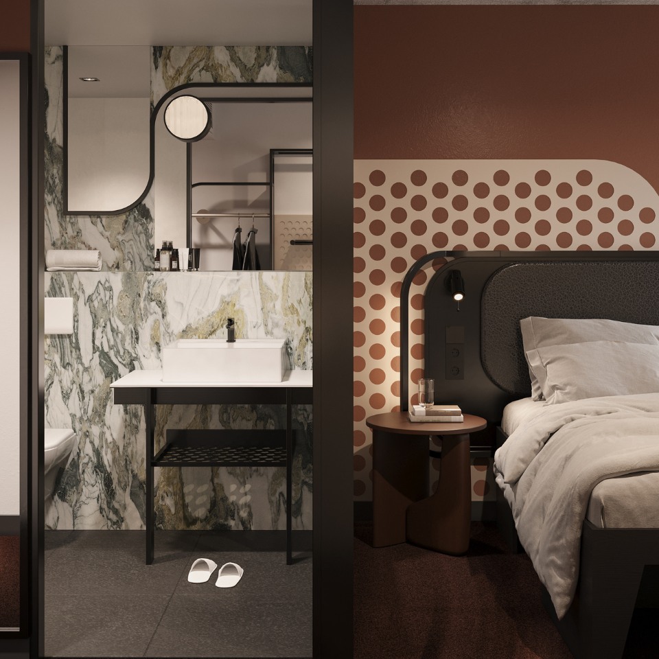 A modern hotel room with a view of the bedroom and bathroom. The bedroom has a patterned wall, cozy bed, and nightstand. The bathroom features a sleek sink, marble wall, and slippers. The design is contemporary and warm.