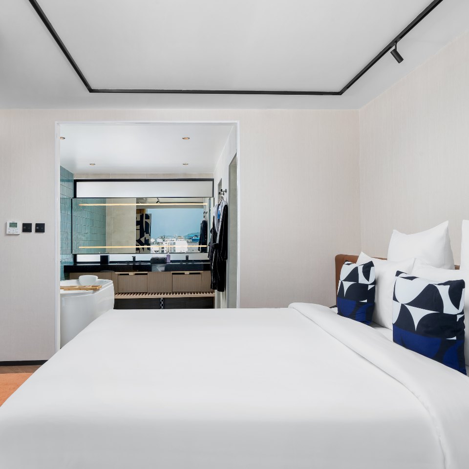 Two beds in a white room with blue patterned cushions.