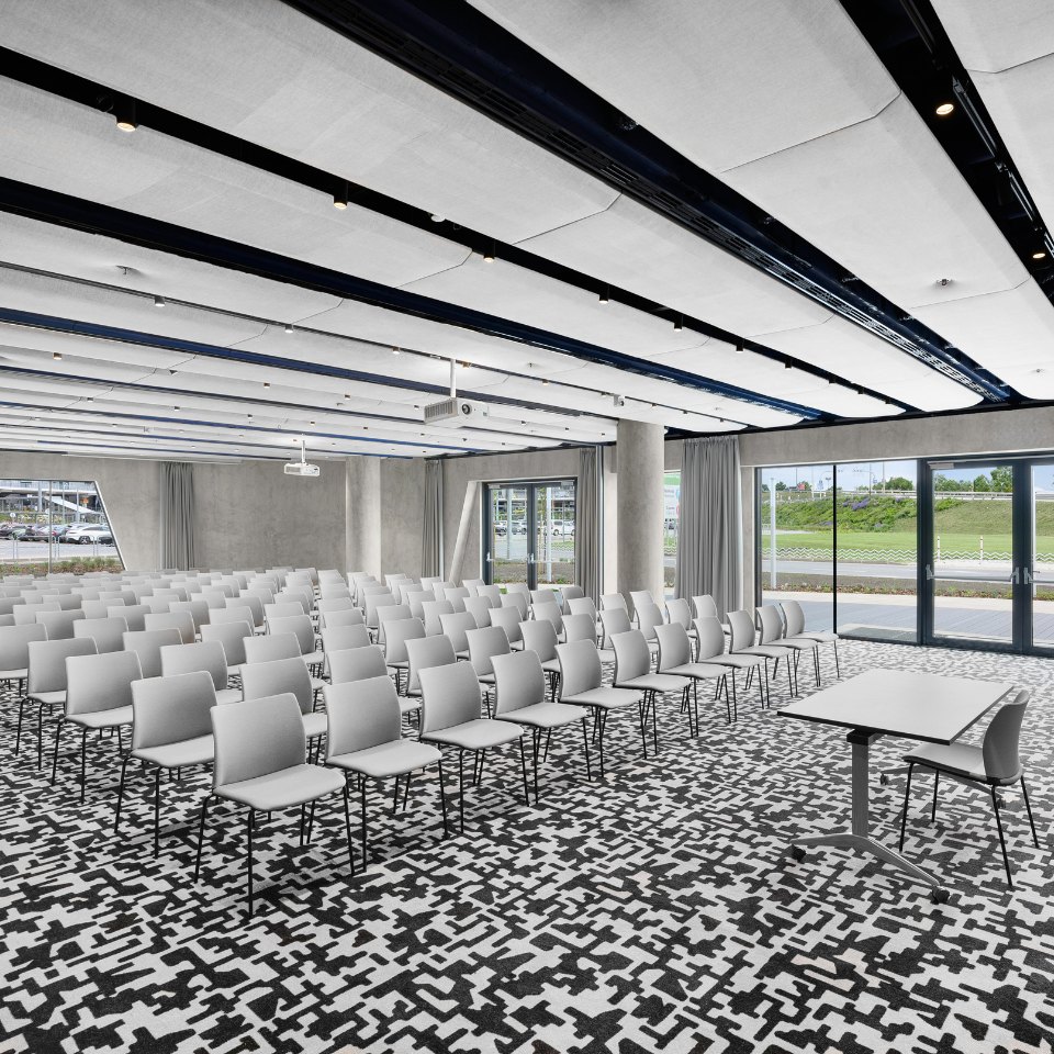 Rows of white chairs in a large conference room with patterned carpet.