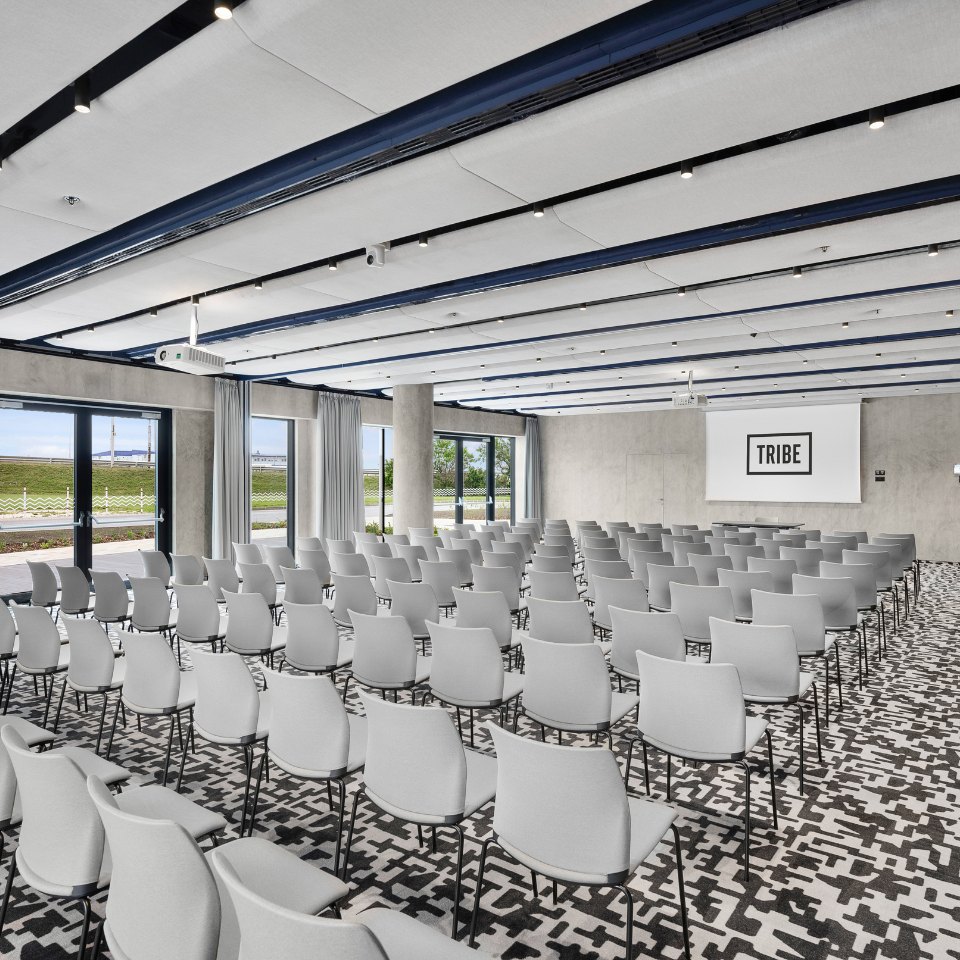 White conference chairs facing a stage and screen.