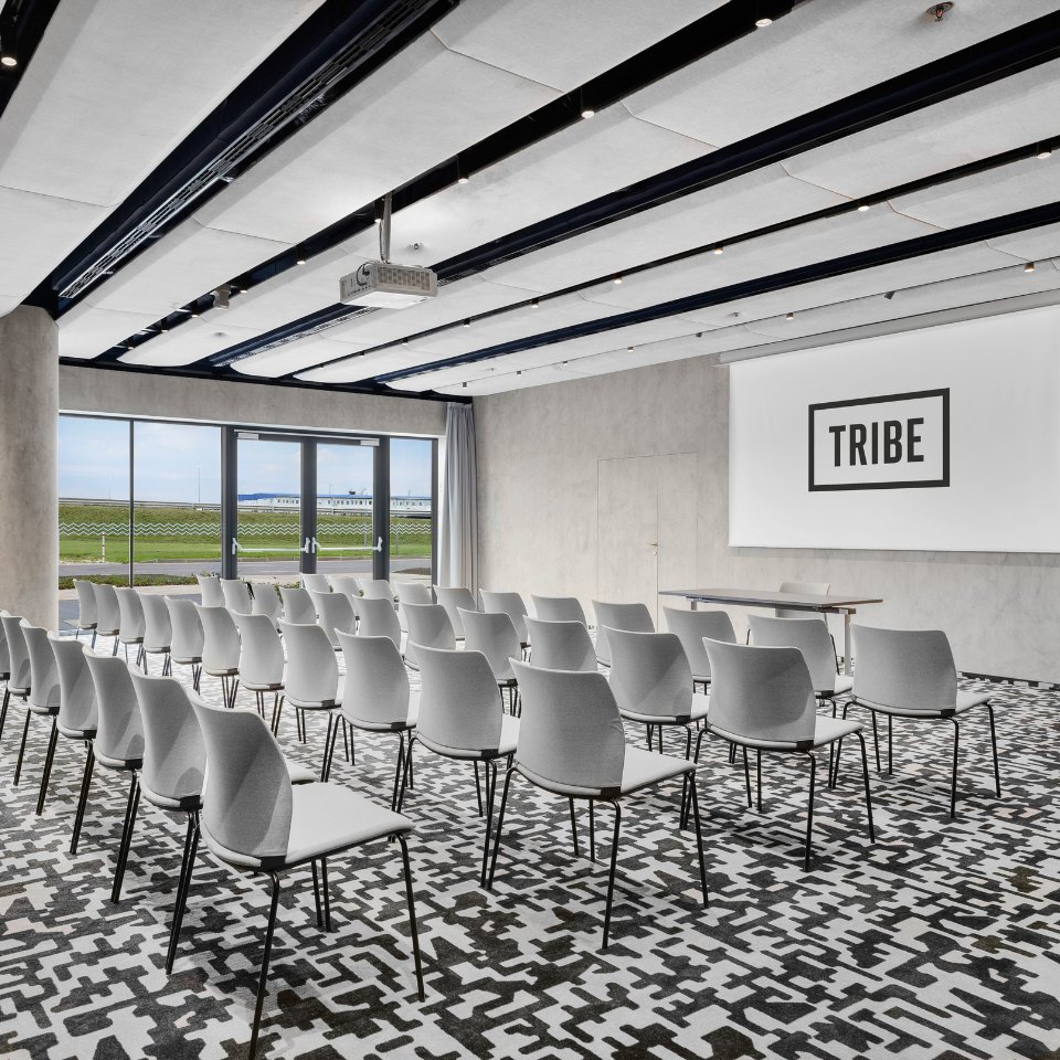 Rows of white conference chairs beside large windows.